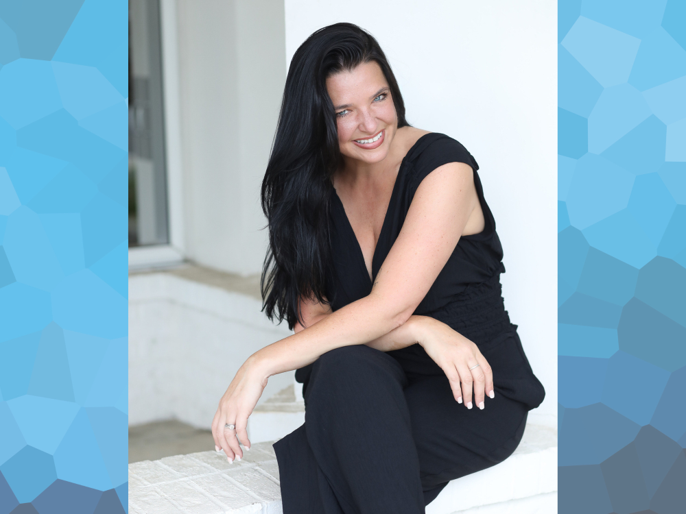 A woman wearing a black shirt and pants sitting in front of a white background.