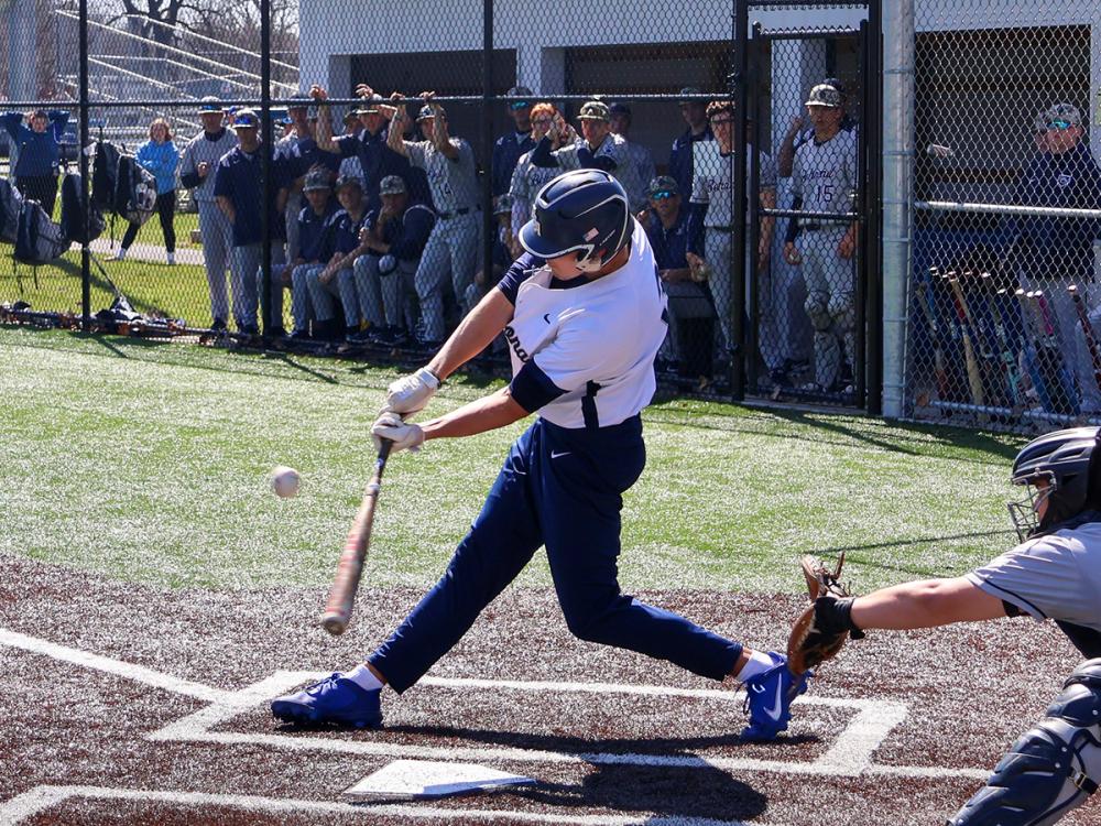 Jonathan Rauch swings at a pitch during a Penn State Altoona baseball game as teammates watch from the dugout