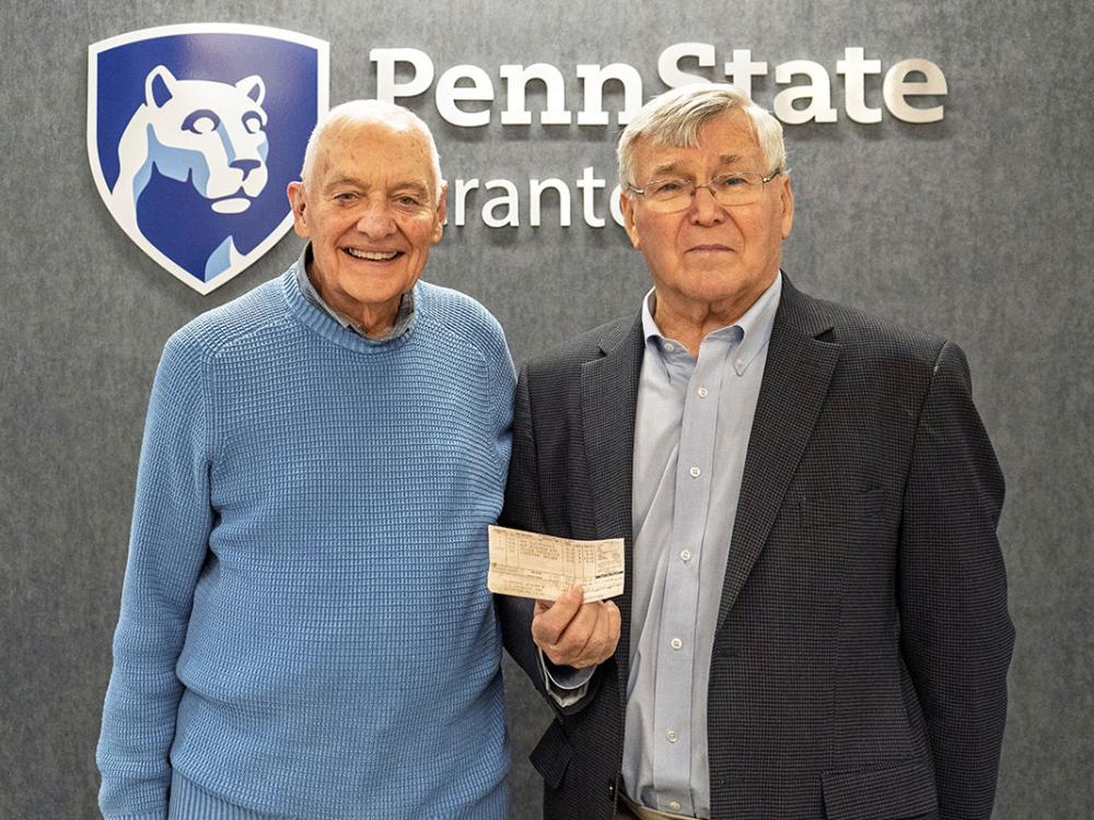 Mike Abdalla and Joe clifford pose for a photo, showing one of Clifford's old grade reports
