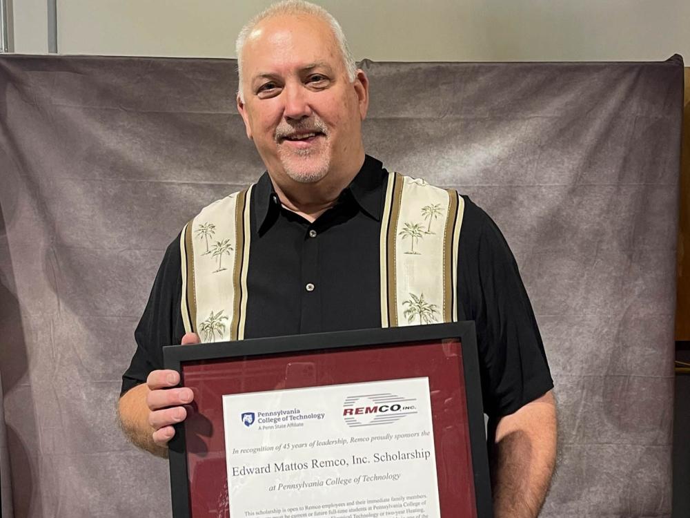 Edward Matto holding a certificate for the new Penn College scholarship endowed in his name.