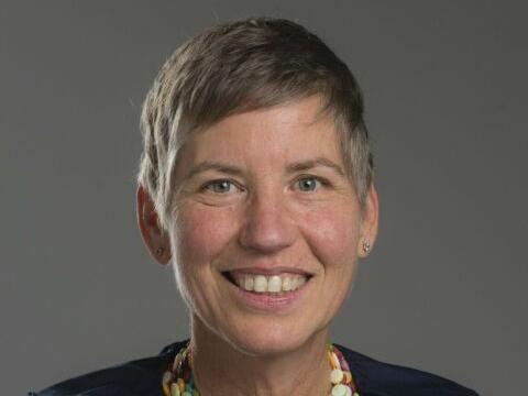 Headshot of woman with short hair, brightly colored necklace