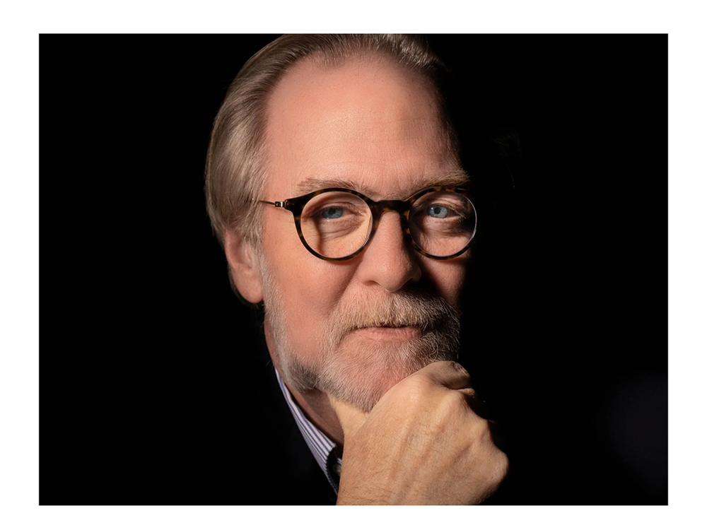 Man wearing glasses with his hand resting on his chin.