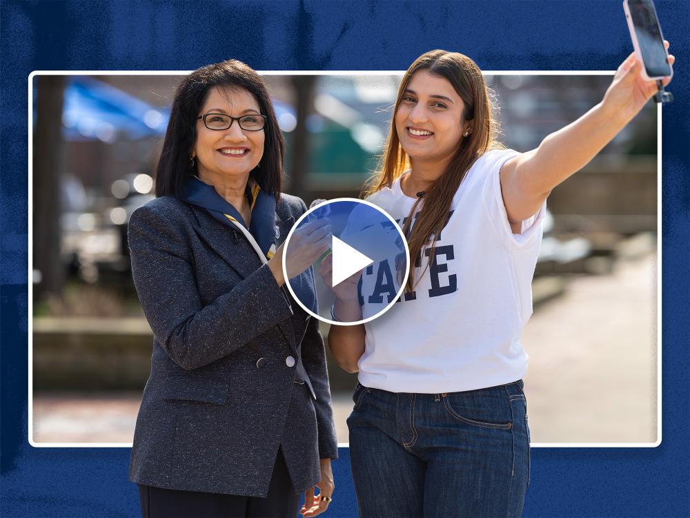 Neeli Bendapudi (left) and student Kavishi Halwavala stand together and Neeli is holding a mic and Kavishi is holding a cell phone.