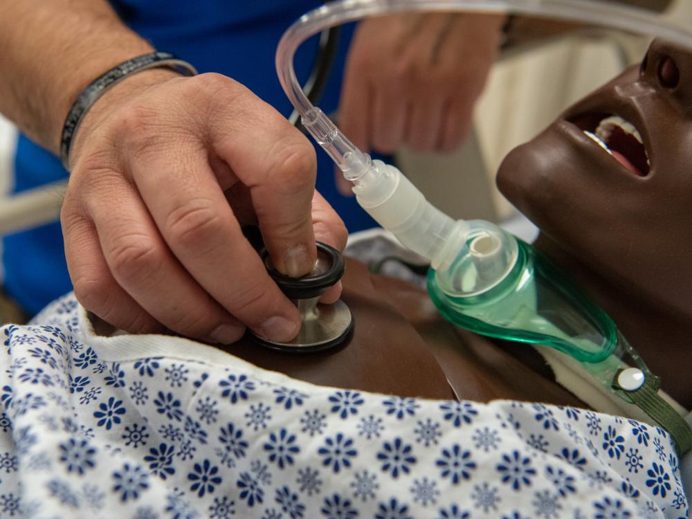 A nursing student works with a dummy patient.