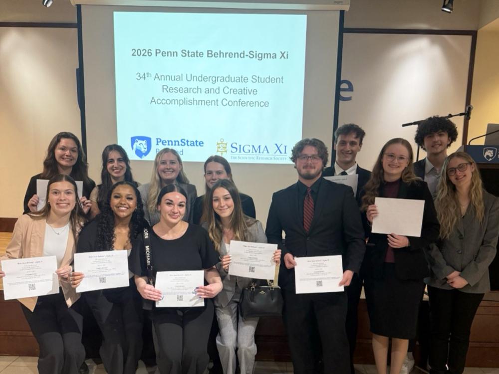 Group of students holding certificates in front of a screen at the 2026 Penn State Behrend Sigma Xi research conference