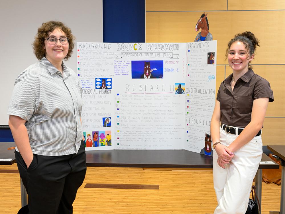 A photo of two students in front of a poster board