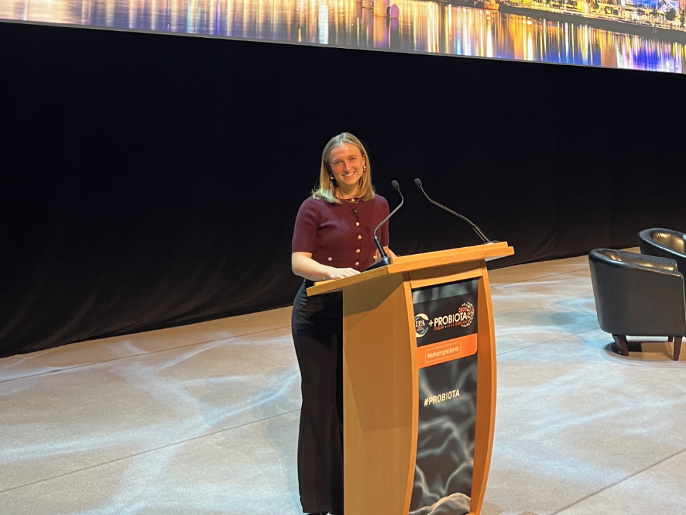 Quinn Burnett standing at a podium and speaking at the conference.