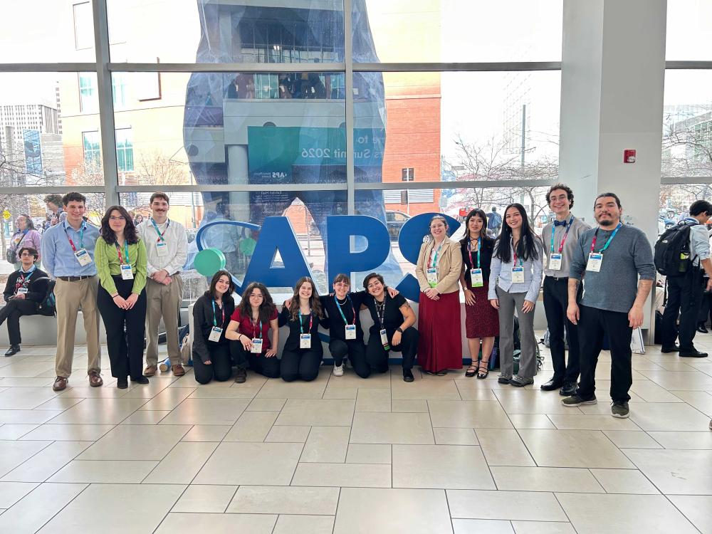 Physics REU students pose in front of the APS sign at a conference