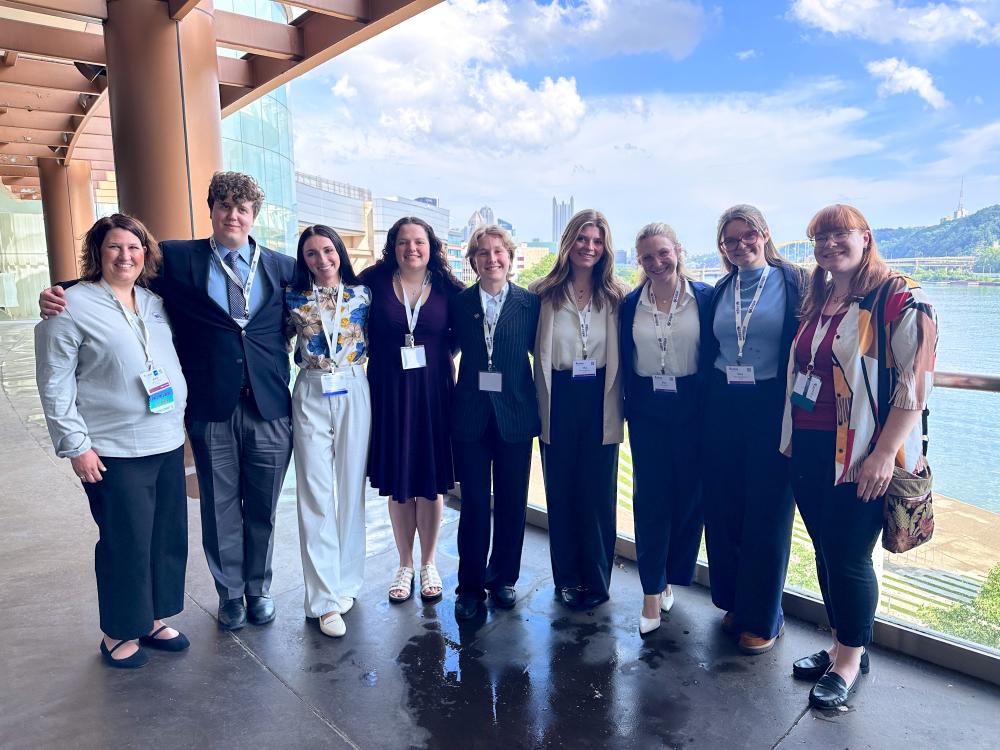 Conference attendees pose in front of the Pittsburgh skyline 