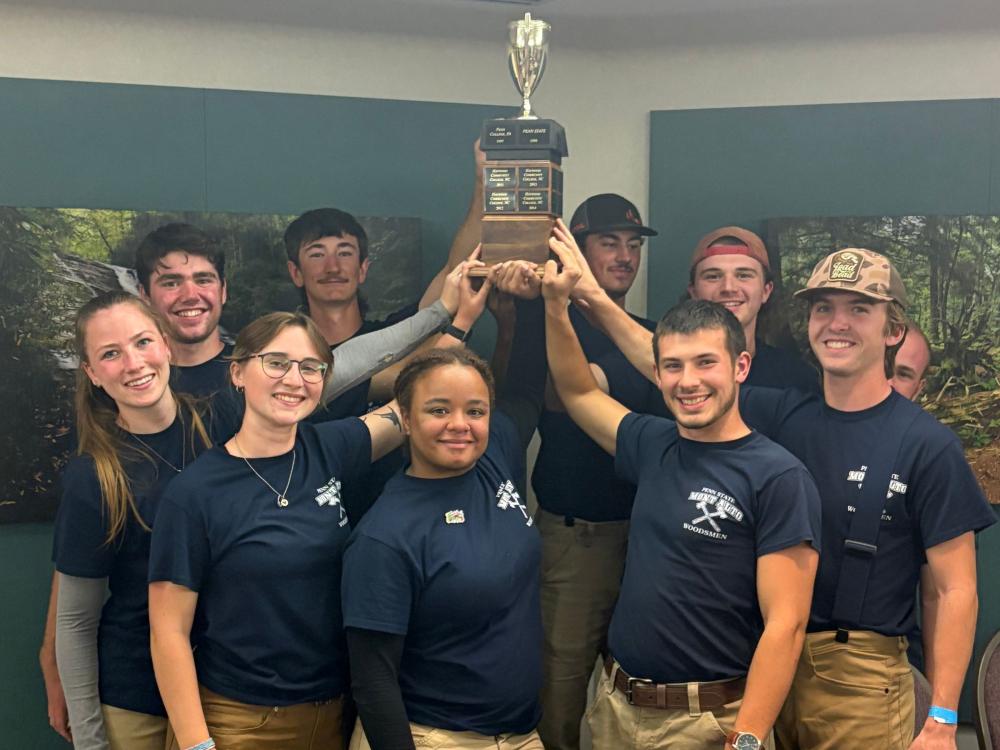 A group of Penn State students are holding a trophy.