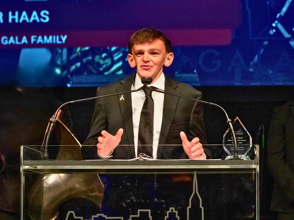 Keynote speaker, Tucker Haas, is standing at a podium in a suit.