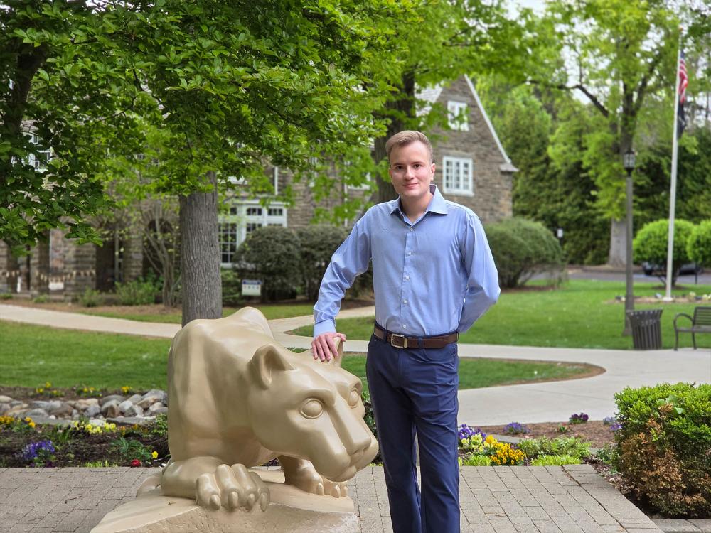 man standing by Nittany lion shrine at Penn State Abington