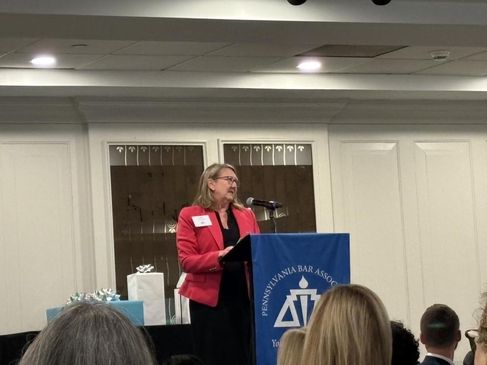 White woman in pink blouse looks to her left at a podium