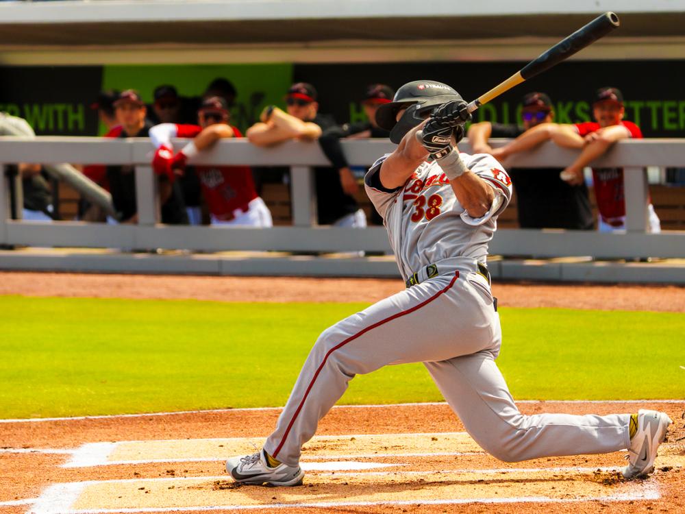 Will Taylor of the Altoona Curve swings at a pitch in front of the dugout during a game.