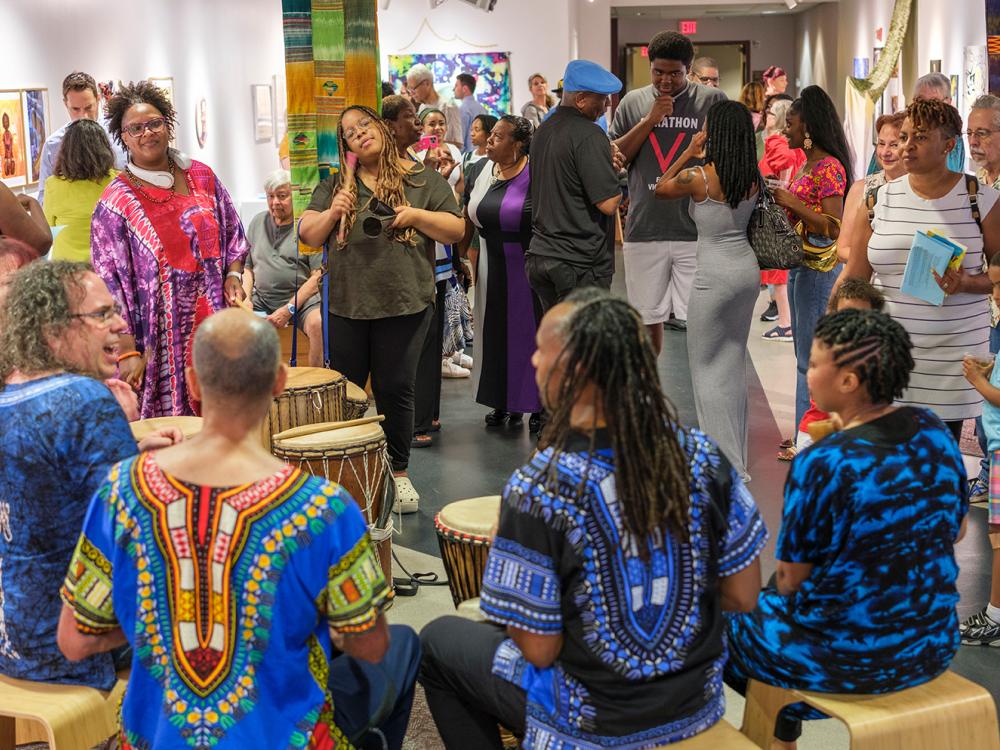 A large group of people hang out together at an event, wearing colorful clothes