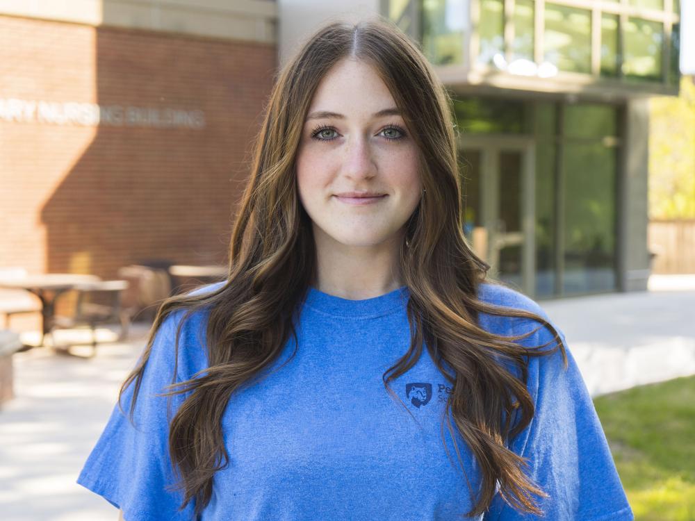 Female student wearing blue shirt smiles for photo.