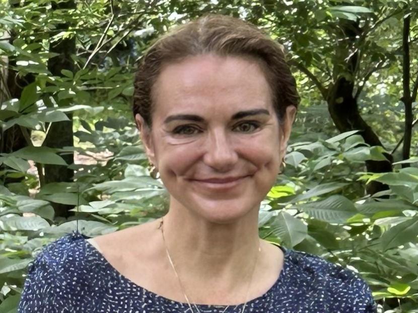 Sarah Brothers standing against a woodsy backdrop