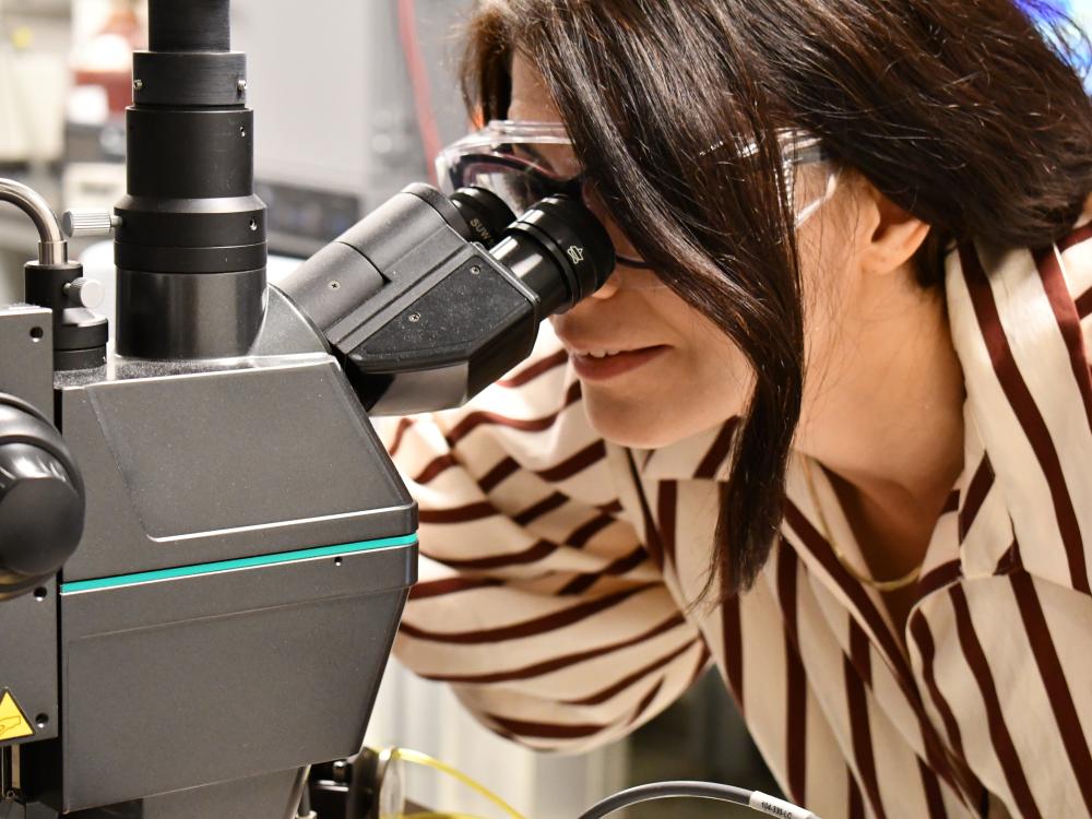 Woman peering through lab equipment
