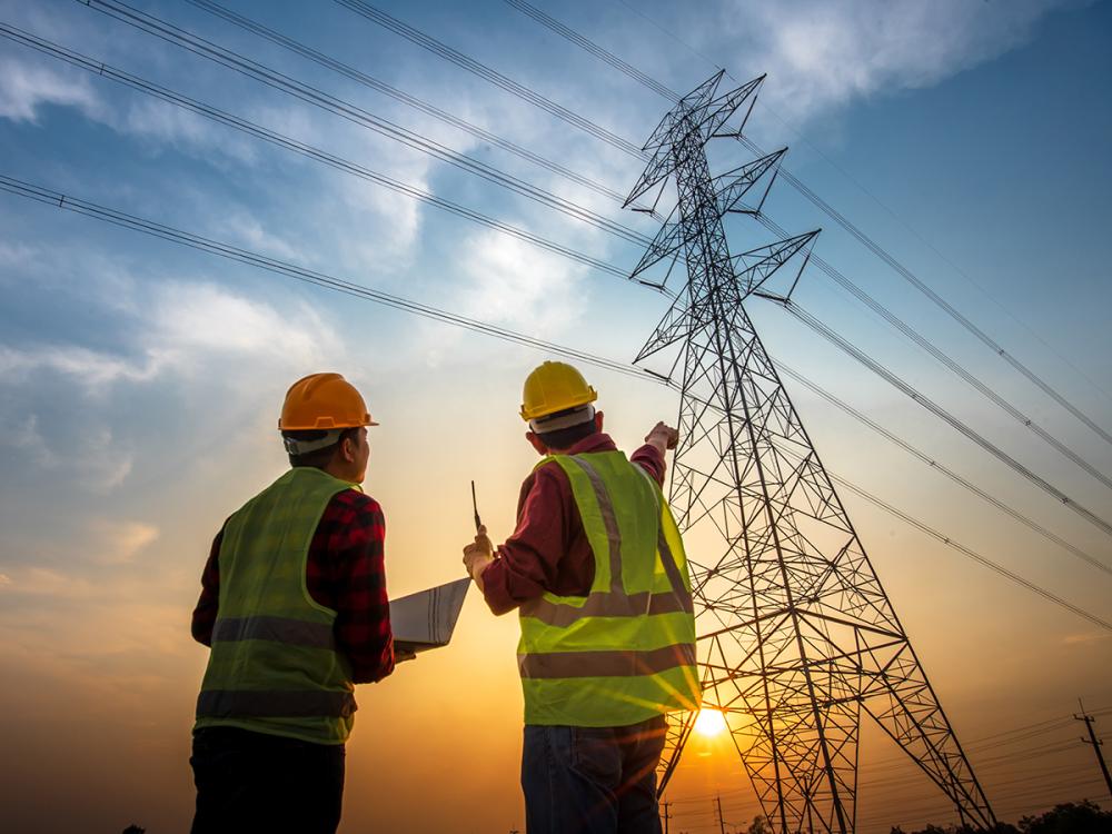 two people look at a transmission tower in the distance
