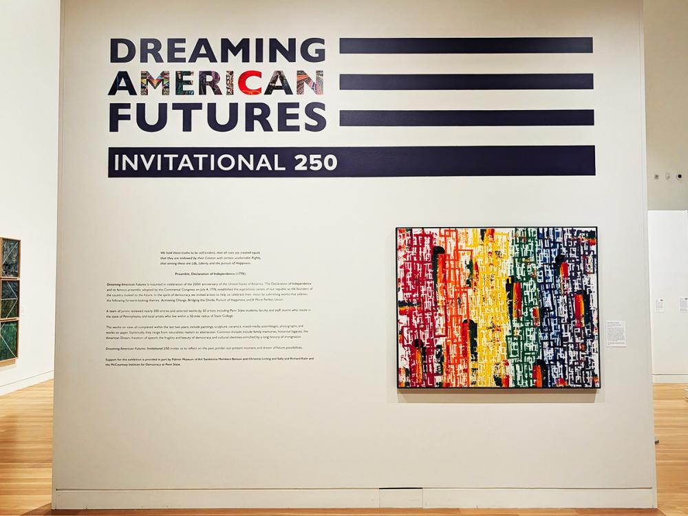 Gallery wall with Dreaming American Futures Invitational 250 text beside a colorful abstract painting.