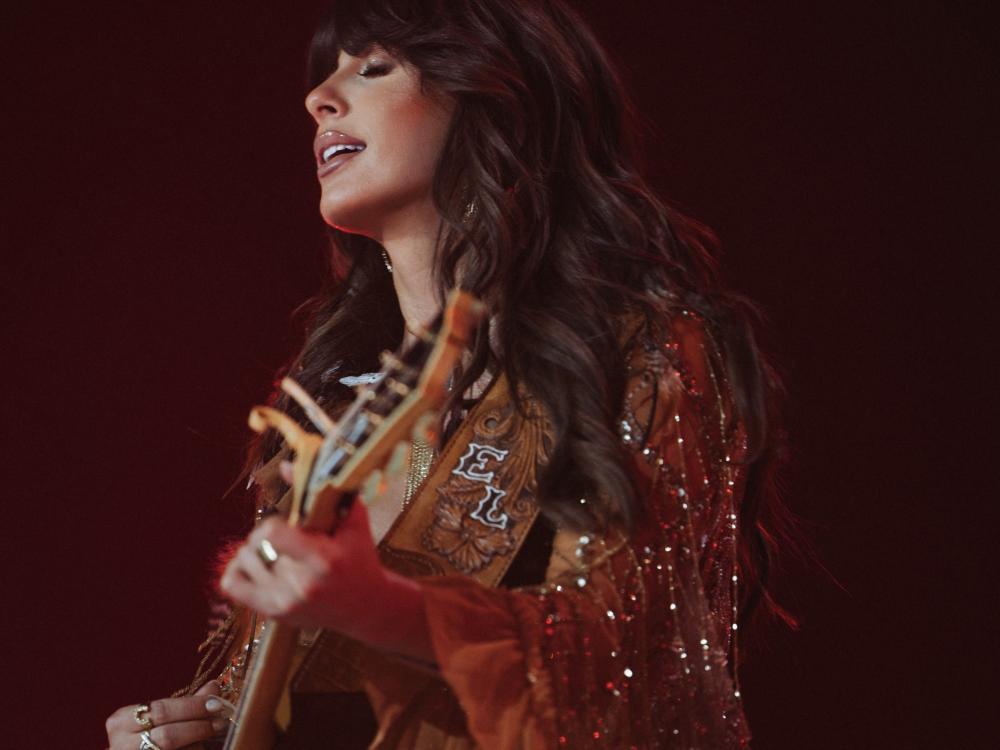 Ella Langley playing guitar and singing with eyes closed.