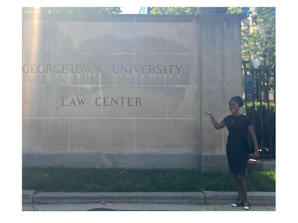 person wearing black dress next to georgetown university law center statue