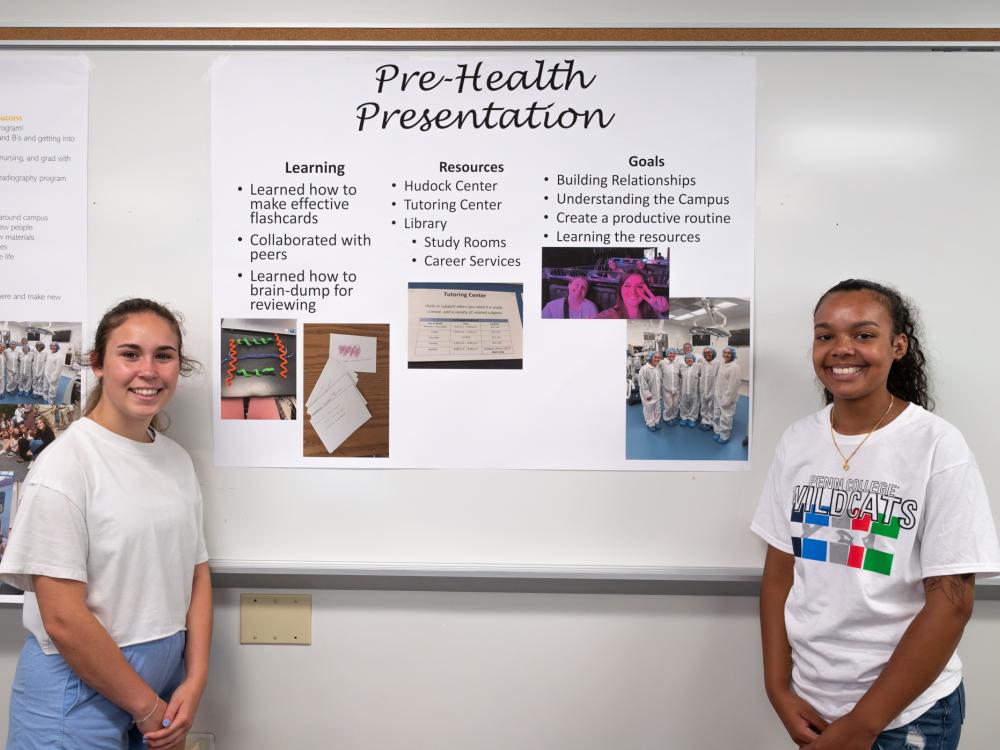 Two stands stand on either side of a poster that says "Pre-Health Presentation.""