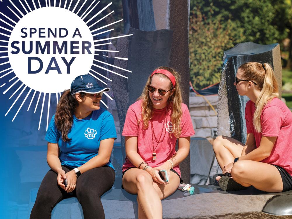 Students sitting outside with a "Spend a Summer Day" sign behind them