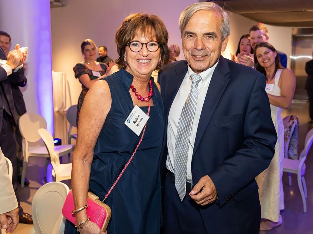 A photo of Sandy Stevens and Randy Woolridge posing together at a gathering