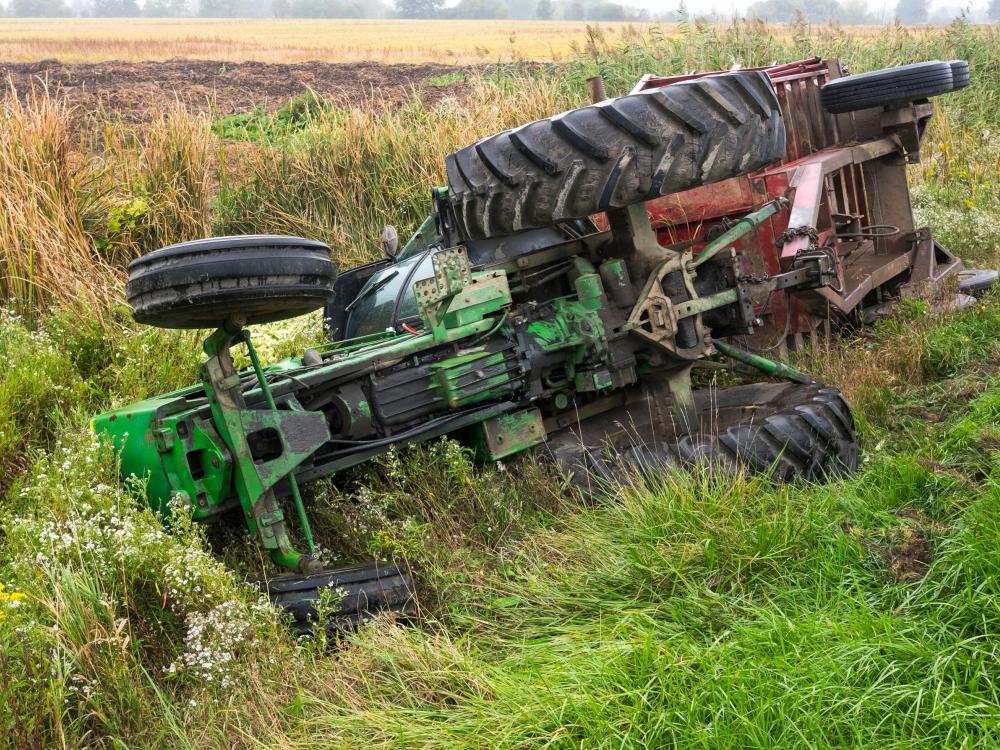 A tractor on its side in a field.