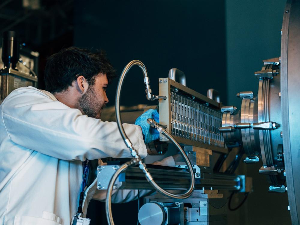 A person makes adjustments to a large piece of lab equipment.