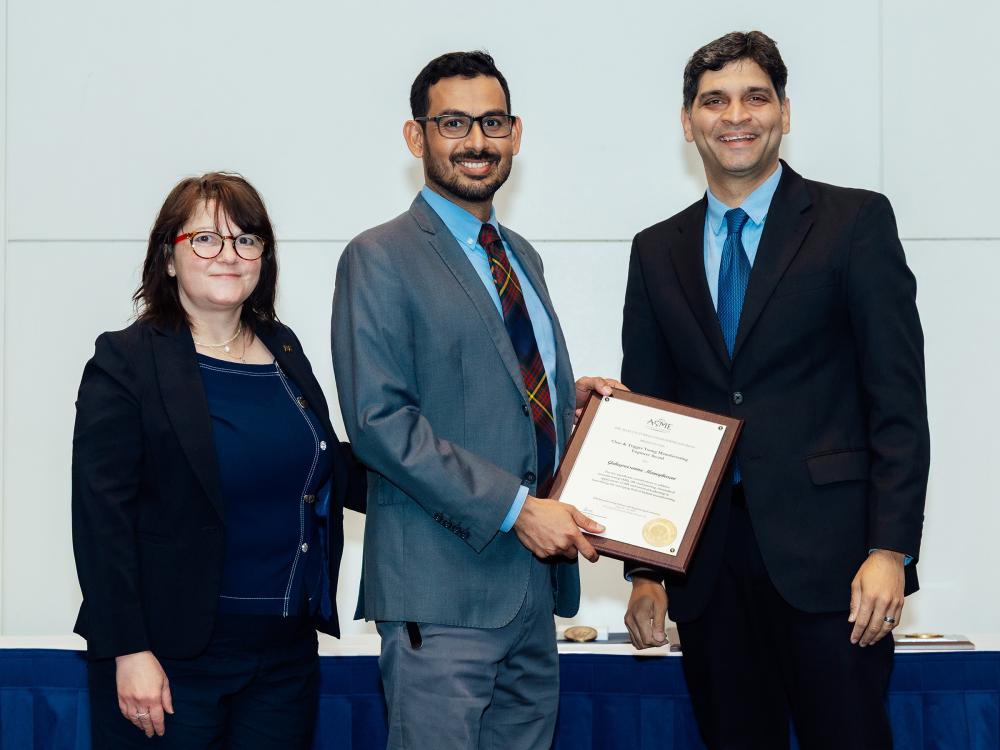 Guha Manogharan accepting an award from two individuals.