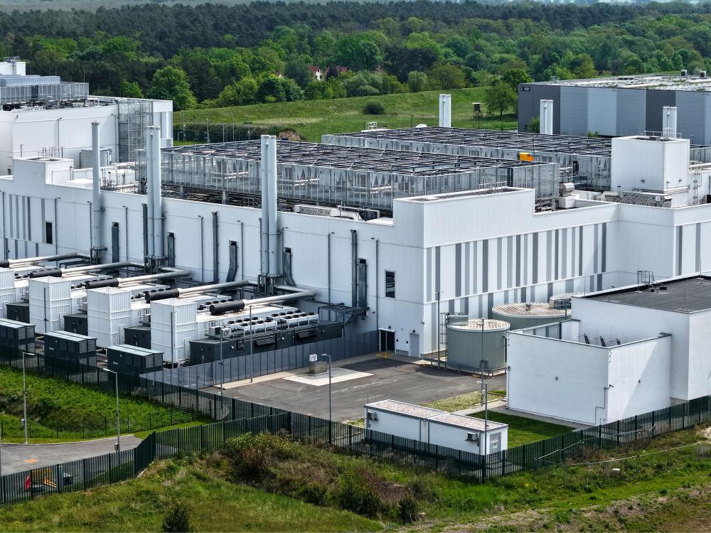 An aerial photo showcasing a large data center facillity, with many cooling units, pieces of piping, and other pieces of technical infrastructure visible