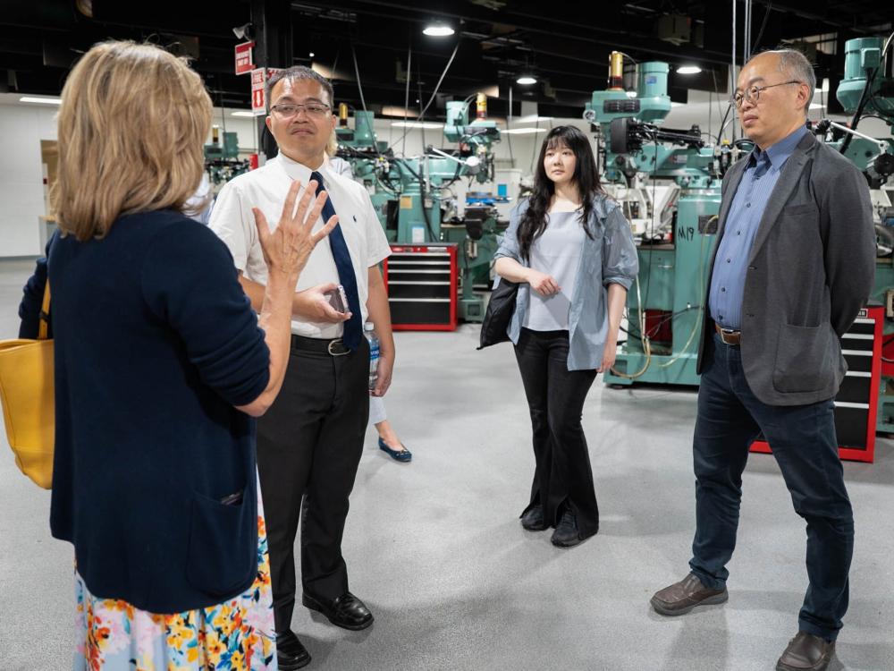 Four people stand together talking in Penn College's Larry A. Ward Machining Technologies Center. They are from Penn College and Taiwan’s National Formosa University.