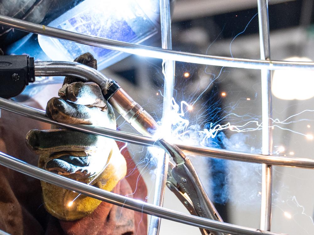 A closeup of a person welding metal bars together