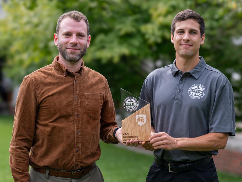 A photo of Herschel Pangborn and Casey Hess holding Pangborn's Outstanding Adviser Award.