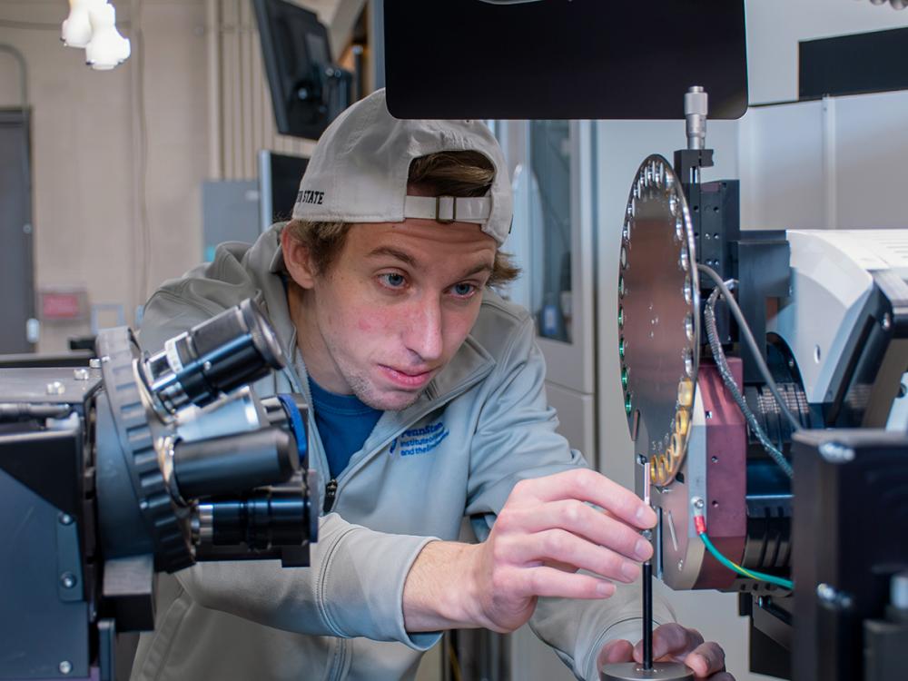 Man places material into a large piece of metal equipment