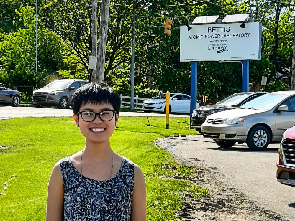 A photo of Ava-Li Baker outside with a sign for a laboratory in the background