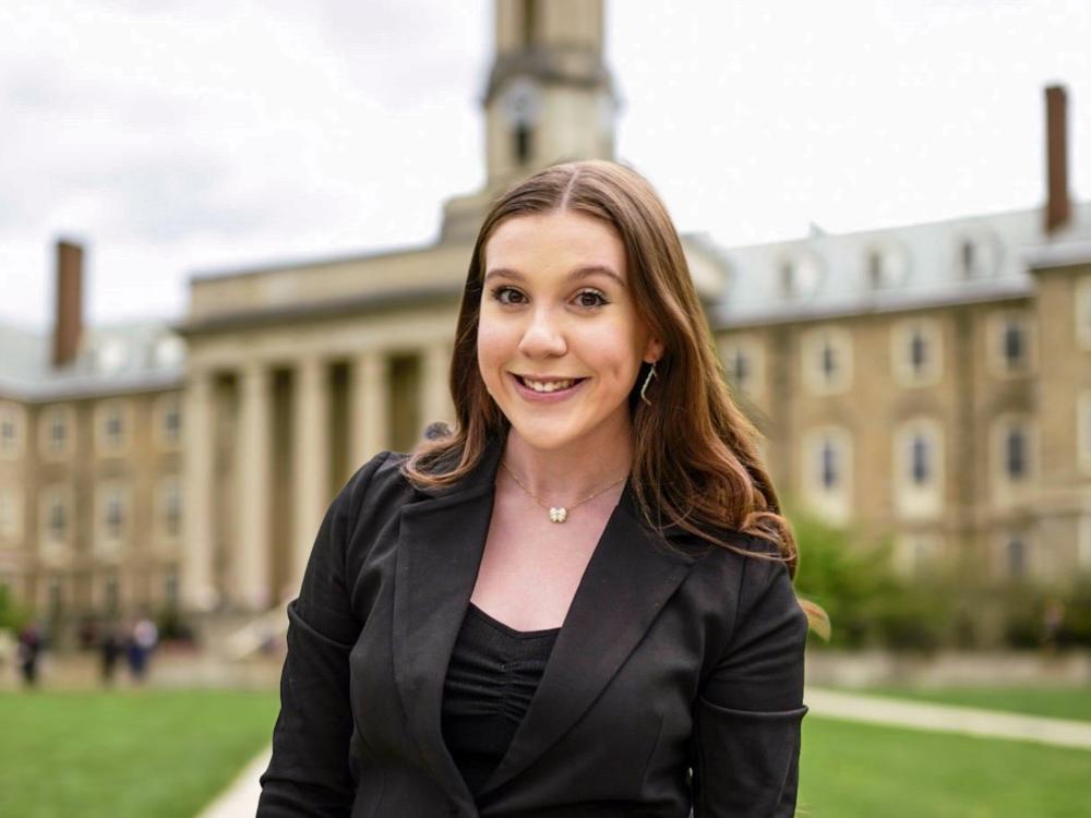 Ella wears an all-black suit while standing in front of Old Main.