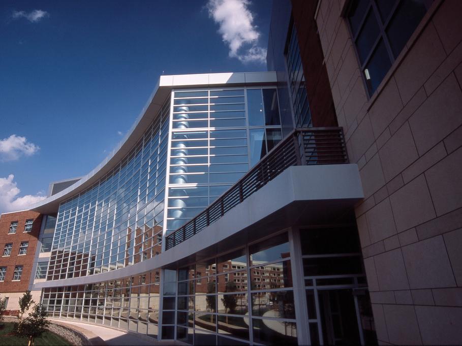 Penn State's Business Building, a modern building with a curved glass façade and a brick section, featuring large windows and a balcony.