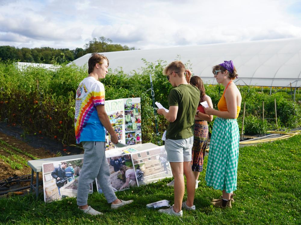 Student Farm Club members show posters and information to students outdoors.
