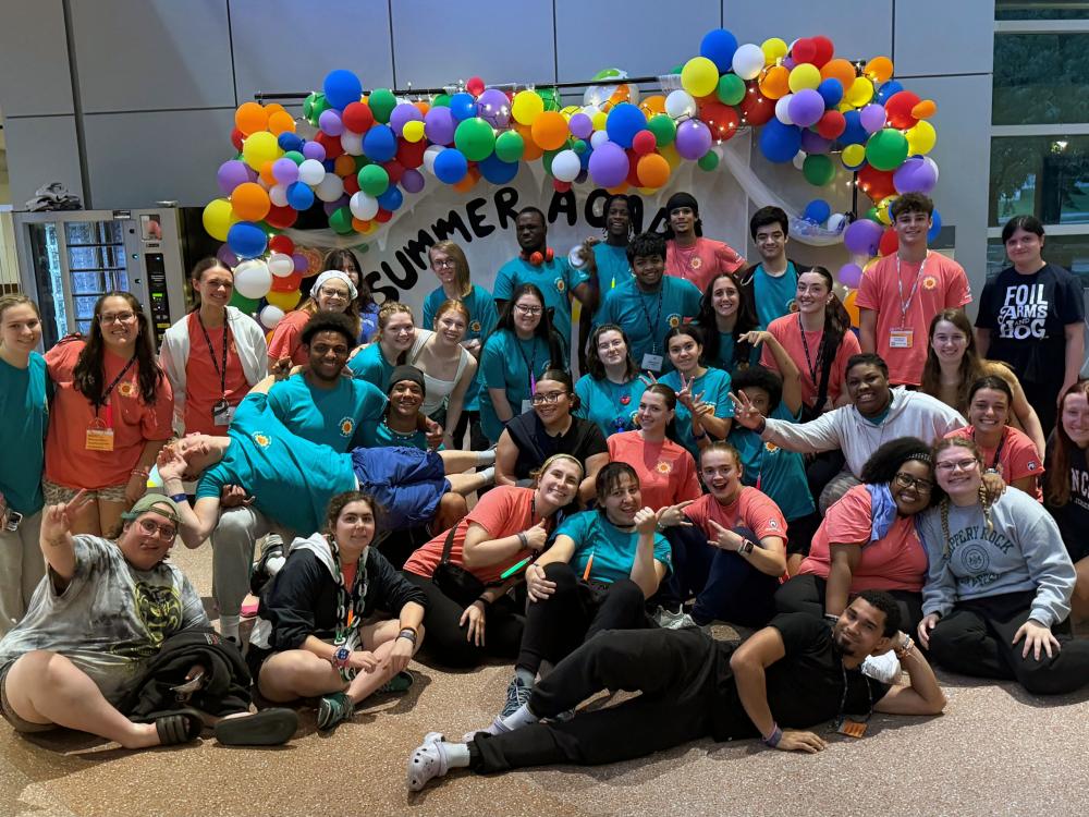 Summer Academy participants, resident assistants and staff pose together beneath a colorful balloon display during the Summer Academy for Students who are Deaf or Hard of Hearing at Penn State.