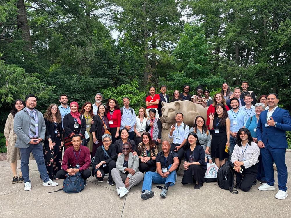 International exchange participants stand and kneel around Penn State Nittany Lion Shrine