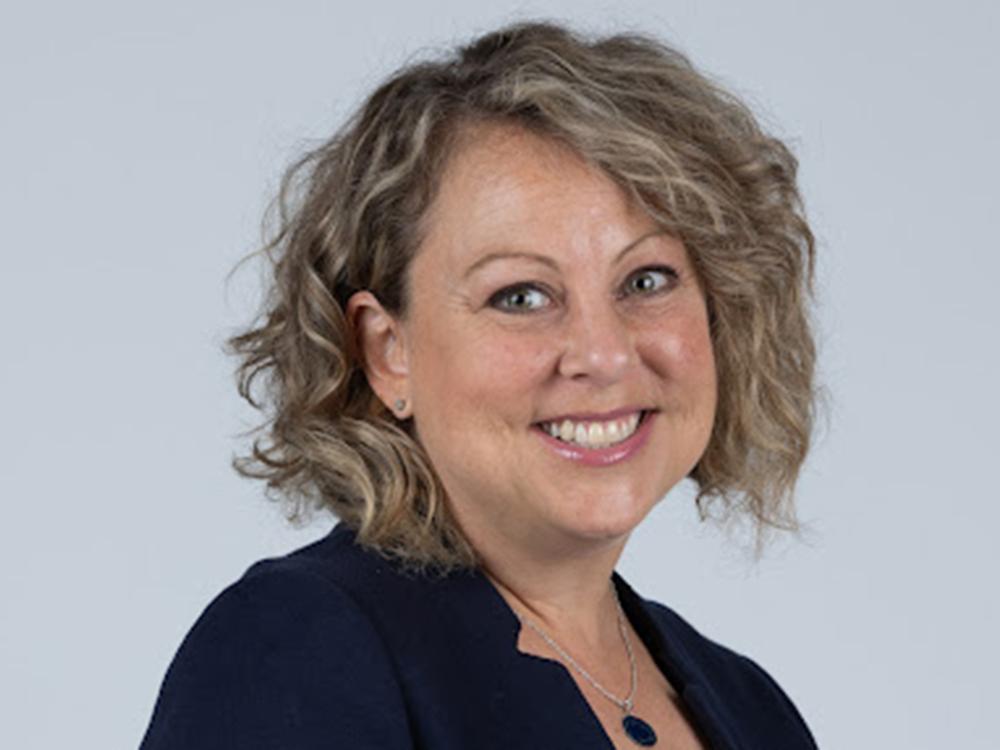 Smilng woman with curly hair and a dark jacket