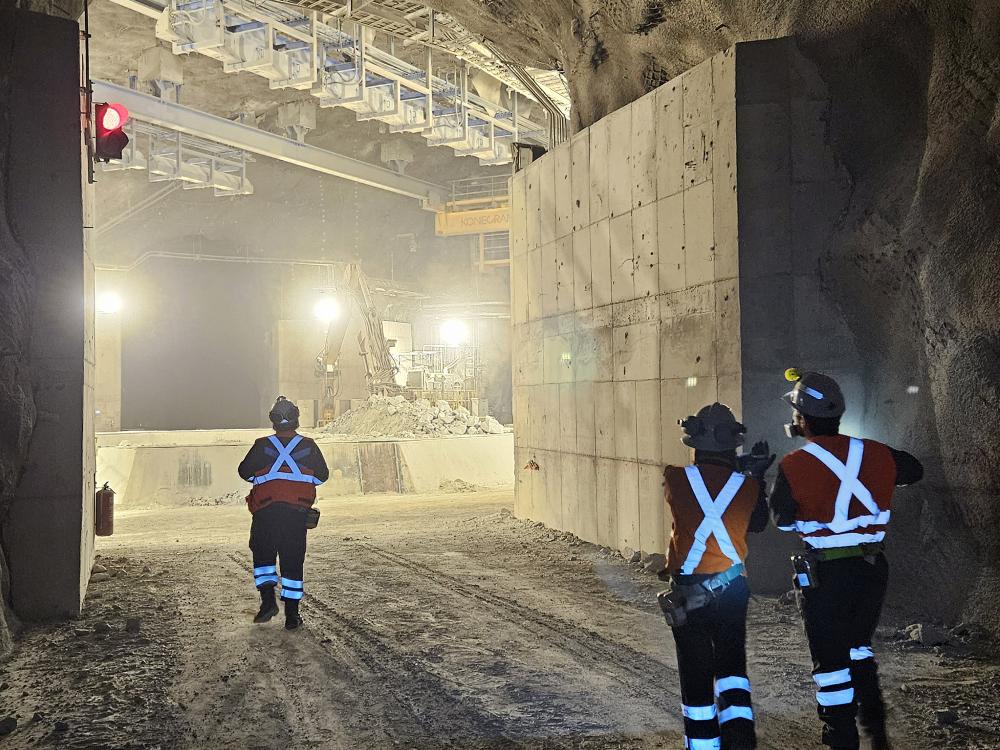 Mining experts in safety gear tour a large underground mine
