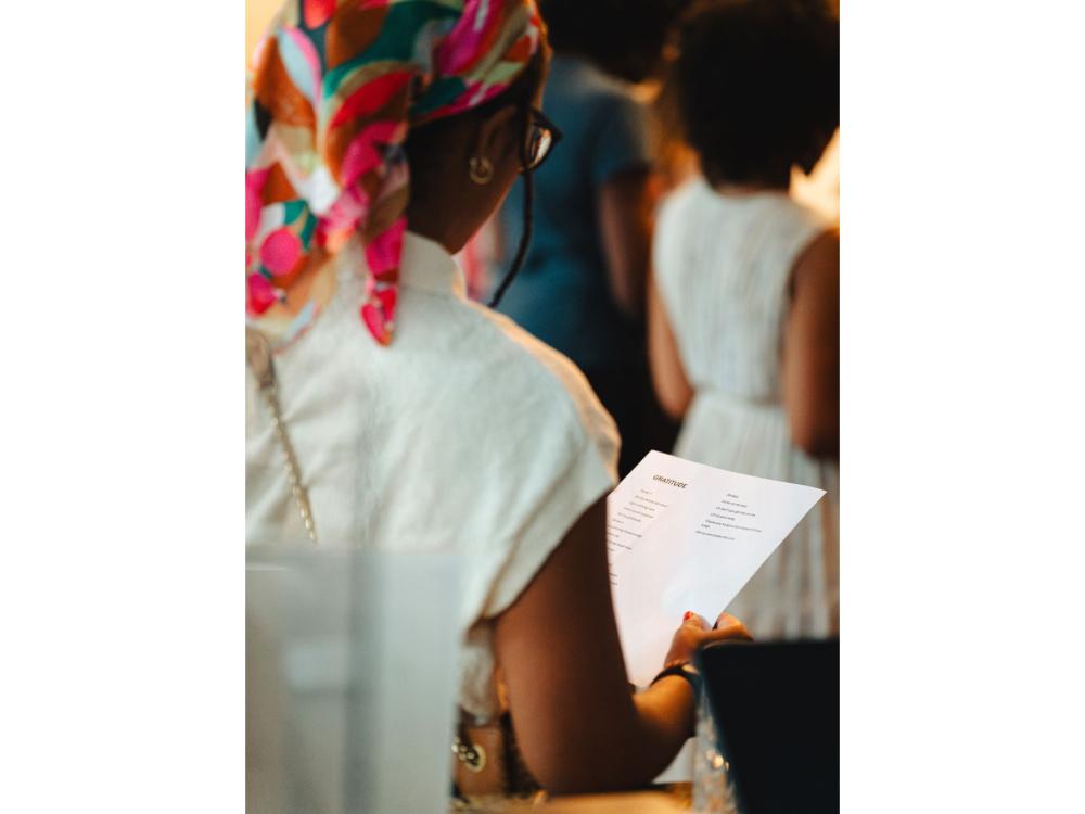 A Black woman looks down at a piece of paper with words typed on it.