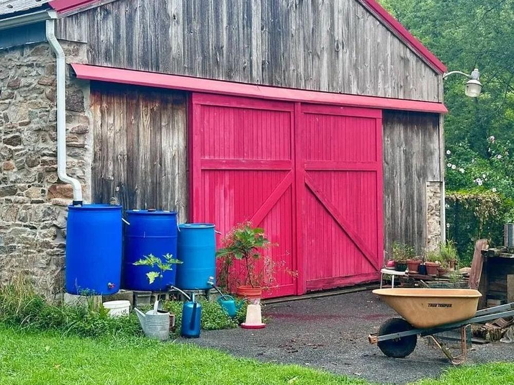 Rain barrels standing outside of a barn