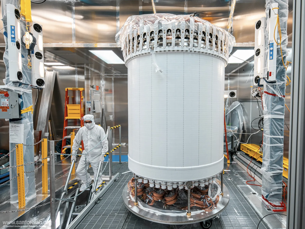 a person in a cleansuit standing by a large while cylindrical machine