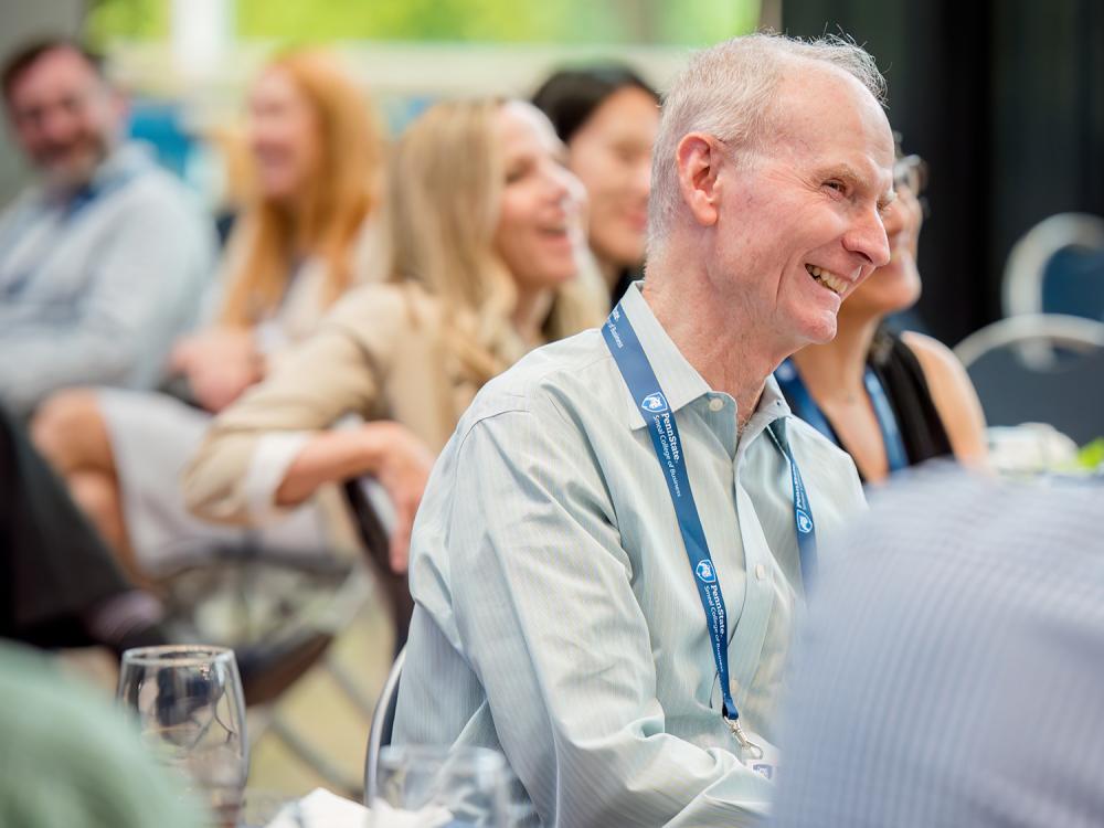 A smiling Don Hambrick sits in a room full of other smiling people.