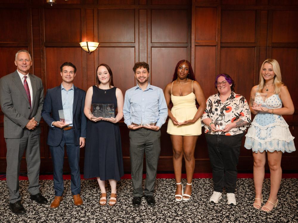 A group of people pose for a photo holding their awards